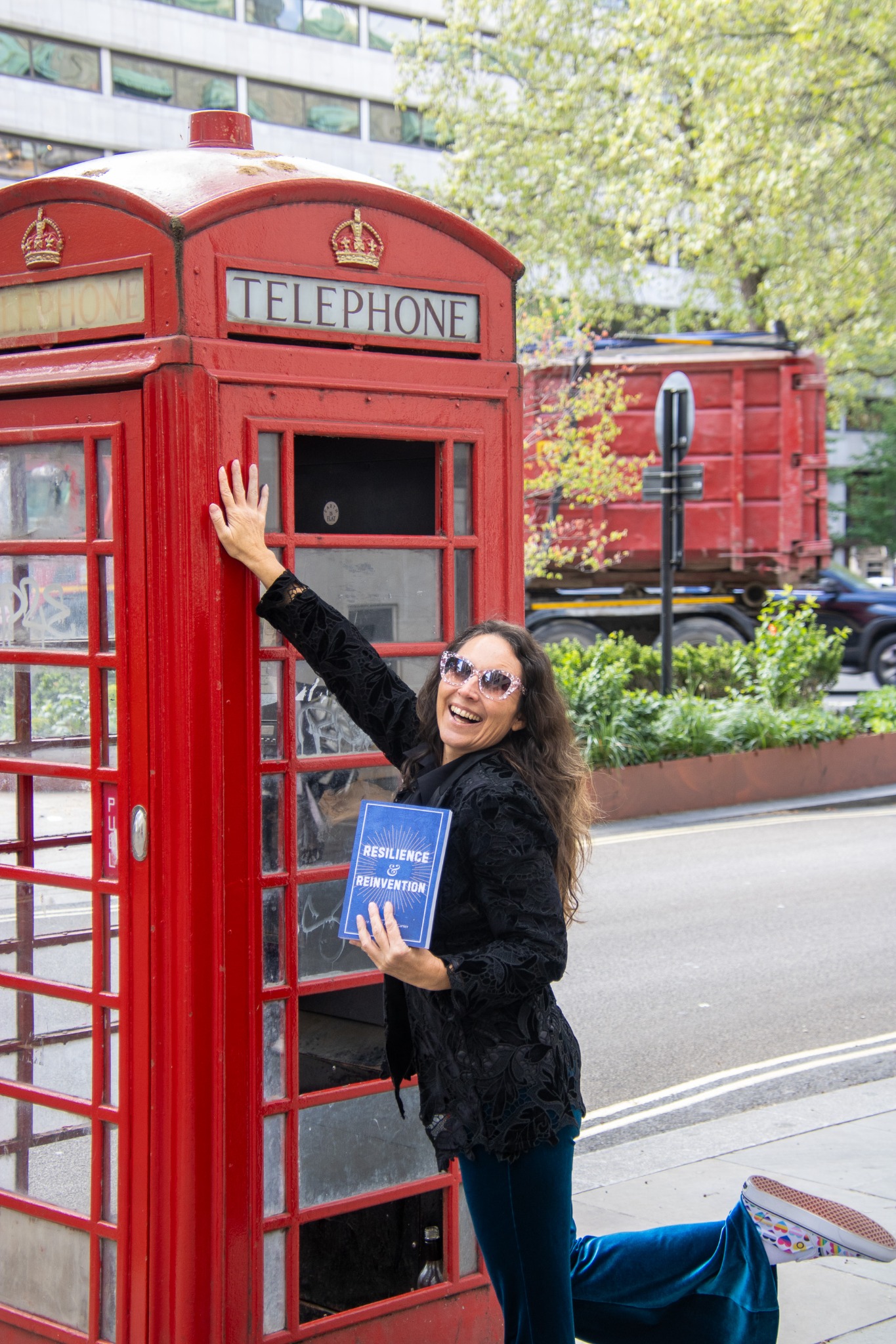 Tanya Hicks holding Resilience & Reinvention beside a red telephone box in London