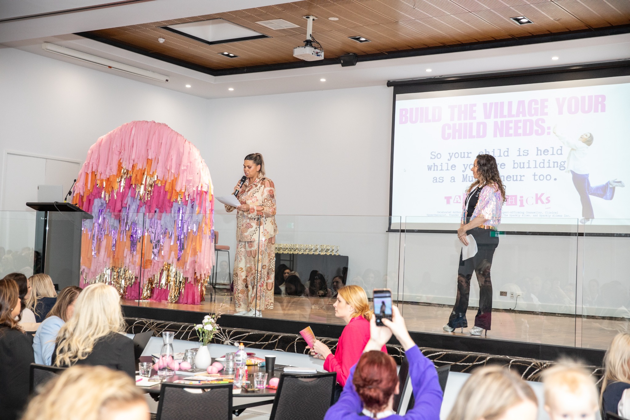 Tanya Hicks on stage at AusMumpreneur in Geelong, 2025, beside a presentation and another speaker
