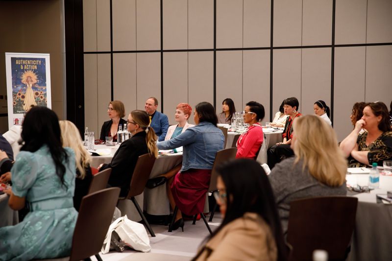 An audience listening at round tables during a Women Changing the World session